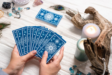 Fortune teller woman and a blue tarot cards over white wooden table background.