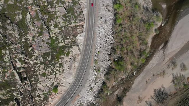 Aerial view over a highway in the mountains near a mountain river.