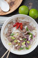 Above view of vietnamese pho bo soup with beef meat, vertical shot on a brown stone background