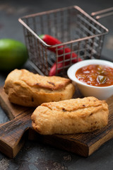 Close-up of empanadas or deep-fried brazilian patties on a wooden serving board, vertical shot