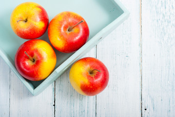 apples at blue tray, white wood table