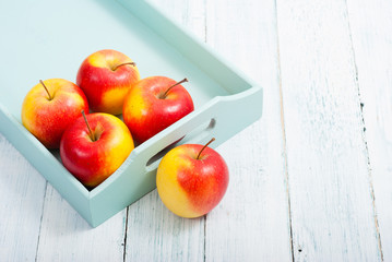 apples at blue tray, white wood table