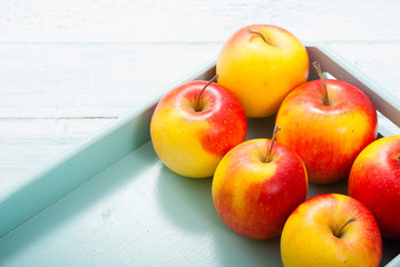 apples at blue tray, white wood table