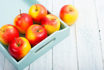 apples at blue tray, white wood table