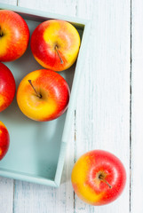 apples at blue tray, white wood table