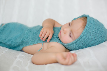 Sweet toddler boy, sleeping with teddy bear toy, cute knitted outfit