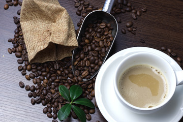 Cup of coffee and coffee beans on a wooden background.