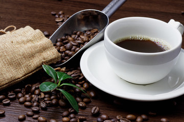 Cup of coffee and coffee beans on a wooden background.