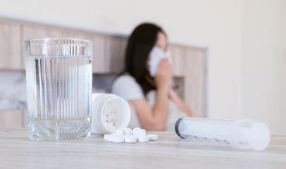 Flu medicine woman Infected With Cold the drug is placed on the table and a glass of water.