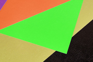 Multicolored sheets of paper on a dark leather background close up