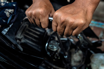 Image is Close up,People are repairing a motorcycle Use a wrench and a screwdriver to work.