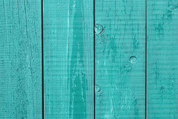 Old painted turquoise wooden fence. Cracked wood timber, blue shabby planks, green flaky grunge background. Oak table. Rustic weathered texture. Natural pattern. Blank space.