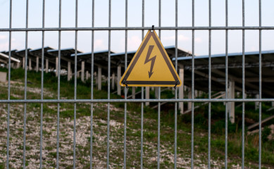 high voltage warning sign at fence of solar field