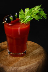 Tomato juice with celery and black olives. black background