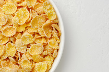 Corn flake in a bowl on white background, quick breakfast.