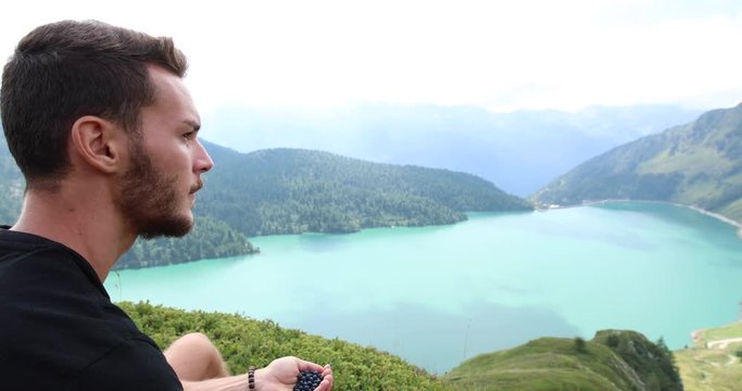 Young man during a hike eats blueberries for a short break. Filmed in the Ritom Lake in Switzerland.
