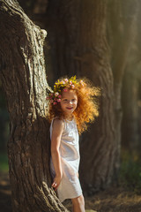 Red hair girl walking into woods with flowers.