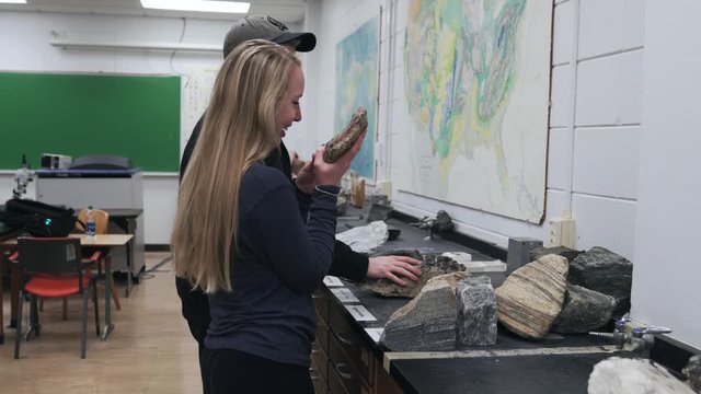 Multiple Students Examine and Discuss big rocks for a geology exam at a College University.