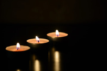 Three burning candles close up in the darkness. Mystery background