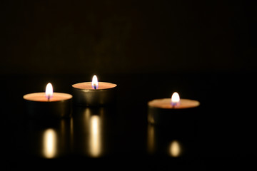 Three burning candles close up in the darkness. Mystery background