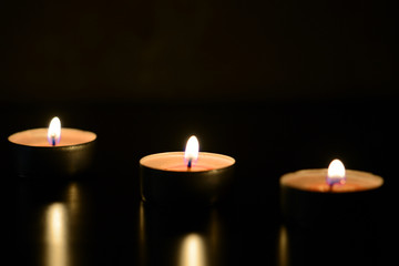 Three burning candles close up in the darkness. Mystery background