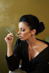 Obraz premium Beautiful fashion Nude confident woman with black hair Smoking a cigarette sitting on a chair in a black jacket. Perfect body smooth clean skin. Stylish portrait of a woman
