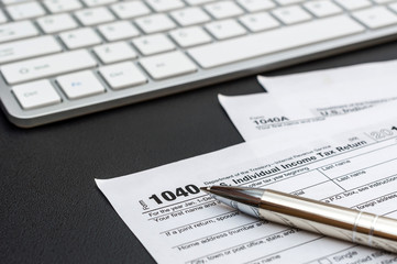 Tax form with computer keyboard and pen at workplace.