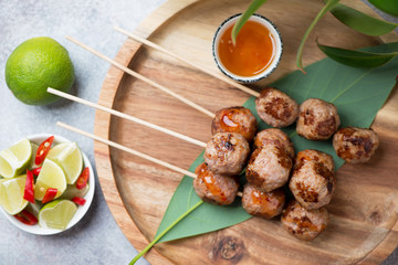 Close-up of fried vietnamese pork meatballs on skewers or nem nuong on a bamboo tray, view from above