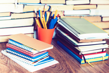 Notebooks piles, stack of books education back to school background, textbooks, glasses and pencils in holder with copy space for text.