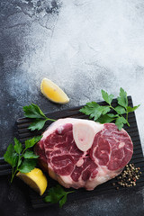 Fresh uncooked cross cut veal shank for making osso buco, flatlay on a light-grey stone background with copyspace, vertical shot