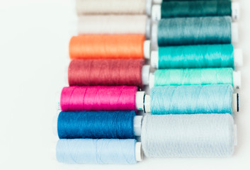 Colored sewing thread coils on white background with copy space for text.