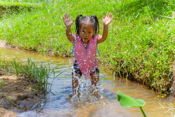 Asian Children playing  barefoot in stream water, play mud and sand.