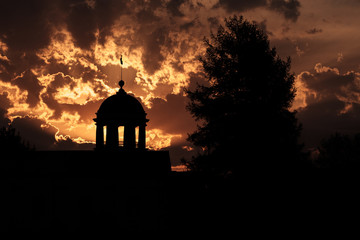 Fototapeta na wymiar silhouettes of trees and heads with columns against the sunset sky