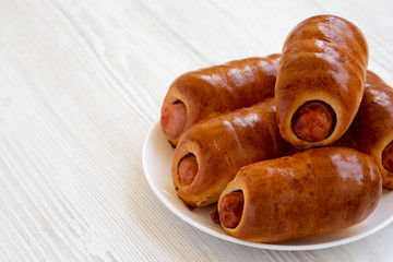 Homemade beef sausage kolache on a white plate on a white wooden surface, low angle view. Copy space.