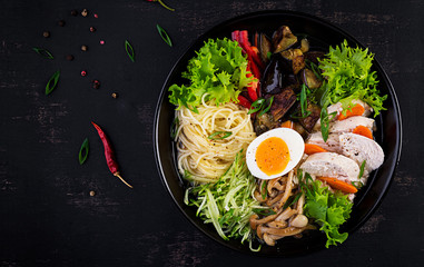 Japanese ramen soup with chicken, egg, shimeji mushrooms and eggplants on dark wooden background. Chanko nabe, sumo soup. Top view