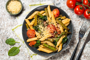 Vegan pasta penne with spinach, asparagus and tomato.