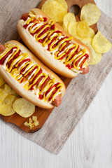 Homemade colombian hot dogs with pineapple sauce, yellow mustard and mayo ketchup on a rustic wooden board, top view. Flat lay, from above, overhead. Copy space.