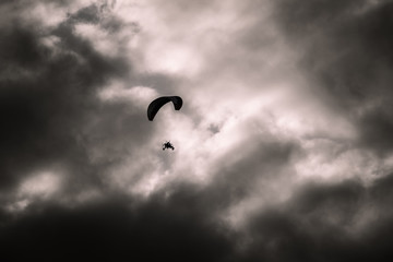 Man flying a paraglider against the clouds