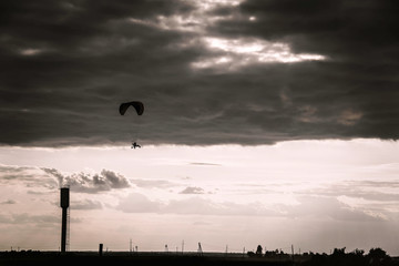 Man flying a paraglider against the clouds
