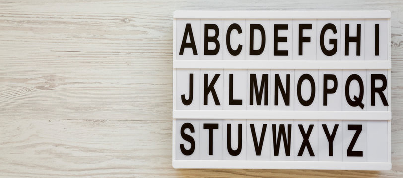 English alphabet on a modern board over white wooden surface, top view. Letters from A to Z. Back to school concept. From above, flat lay, overhead. Copy space.
