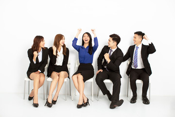 happy asian business people sitting on the chairs in a row