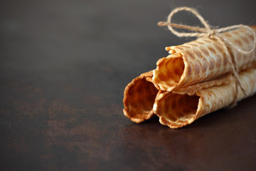 Waffle rolls tied with rope three pieces on a dark tabletop.