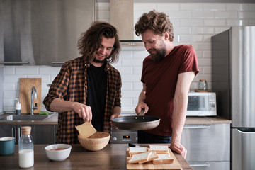 Gay couple doing dinner in the kitchen together.