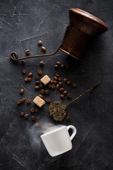 Coffee making  background. Coffee pot, cup coffee with smoke, coffee beans, sugar and sugar tongs, top view, flat lay