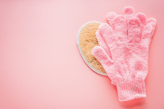 Exfoliating massage glove for shower, sea salt and washcloth on a pink background and space for text