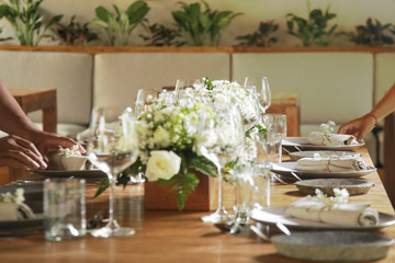 Women hands arranging silver cutlery on a table. Wedding or festive table setting. Beautiful and simple arrangement.  Restaurant concept.