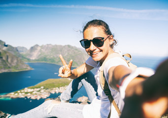 Happy woman hiker doing selfie at the top of Reinebringen hike above Reine village in the Lofoten...