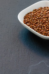 rohe Linsen in weißer Schale auf schwarzem Schiefer