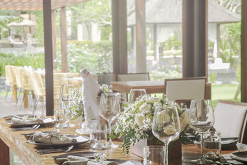 The beautiful arrangement on the wooden table, white roses and ceramic plates. Boho chic wedding table setting. 