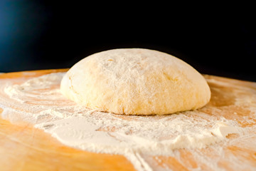 Dough on a wooden Board and with a black background. Gentle dough for baking